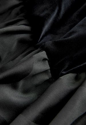 Black fabric with smooth and textured layers, featuring a mix of matte and shiny surfaces in a ruffled design. Soft and flowing appearance.