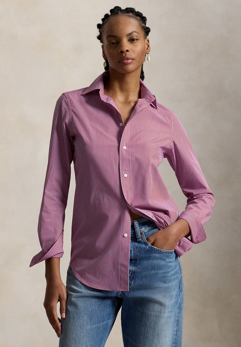 Chemise à boutons rayée rouge et blanc avec un col pointu, des manches longues et une coupe décontractée, associée à un jean denim bleu clair.