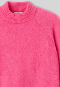 Pull en tricot rose avec un col montant, des manches raglan, une texture douce et une coupe légèrement ample. Comprend une étiquette à l'intérieur du col.