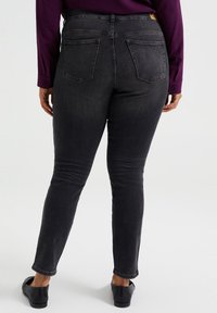 Svarta denimjeans med en åtsittande design, femfickorsstil och medelhög midja. Tyget har en slät textur och lätt stretch.