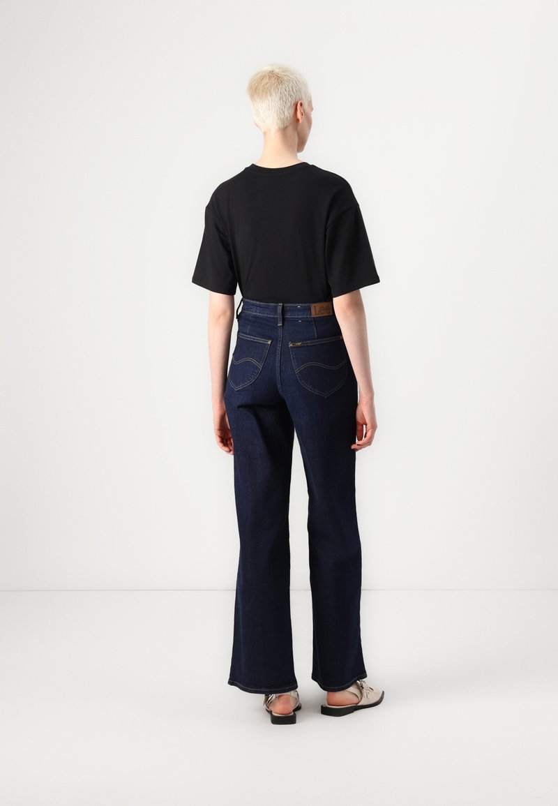 Czarna koszulka z krótkim rękawem w połączeniu z ciemnoniebieskimi dzwonami. Cechami szczególnymi są tylne kieszenie oraz skórzana metka na pasie.