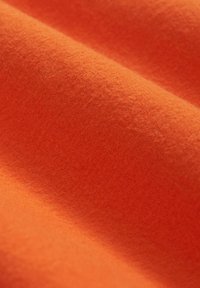 Pomarańczowa filcowa tkanina o miękkiej, teksturowanej powierzchni, ukazująca gładki wzór fal oraz intensywny kolor w całej powierzchni.