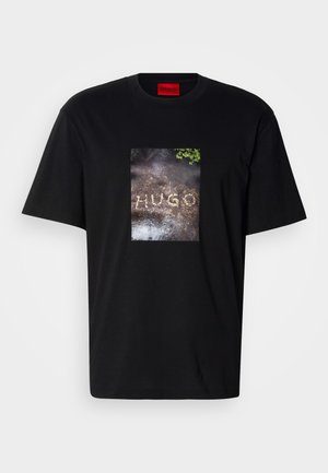 Mustast puuvillast T-särk, millel on ristkülikukujuline graafiline trükk, kus on kujutatud sõna "HUGO" tekstuurse pinna peal. Lühikesed varrukad, ümara kaelusega.