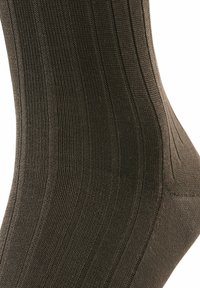 Braune gerippte Socke aus Strickmaterial, ausgestattet mit einer glatten Textur und vertikalen Streifen sowie einer verstärkten Zehen- und Fersenkonstruktion.