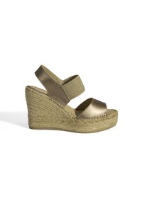 Sandale en bronze avec un talon en jute tissé, présentant une bride métallique brillante et une bande élastique douce pour le soutien autour de la cheville.