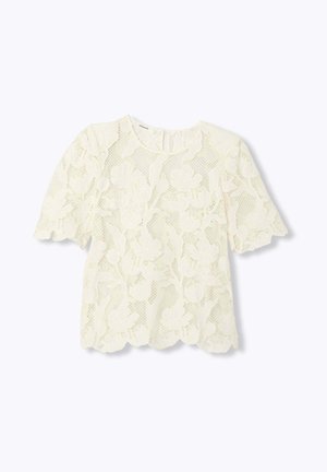Blouse blanche en dentelle à manches courtes avec motif floral, col rond, bords festonnés et fermeture à bouton en forme de trou de serrure au dos.
