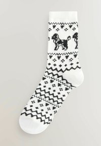 Weiße Socken mit schwarzen Mustern, die Hunde und Herzen zeigen. Strickdesign mit einer strukturierten Oberfläche und geripptem Bündchen.
