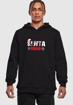 Sort hættetrøje med teksten "SANTA SQUAD" i røde, hvide og mønstrede bogstaver. Indeholder en frontlomme og snøre til hætten.