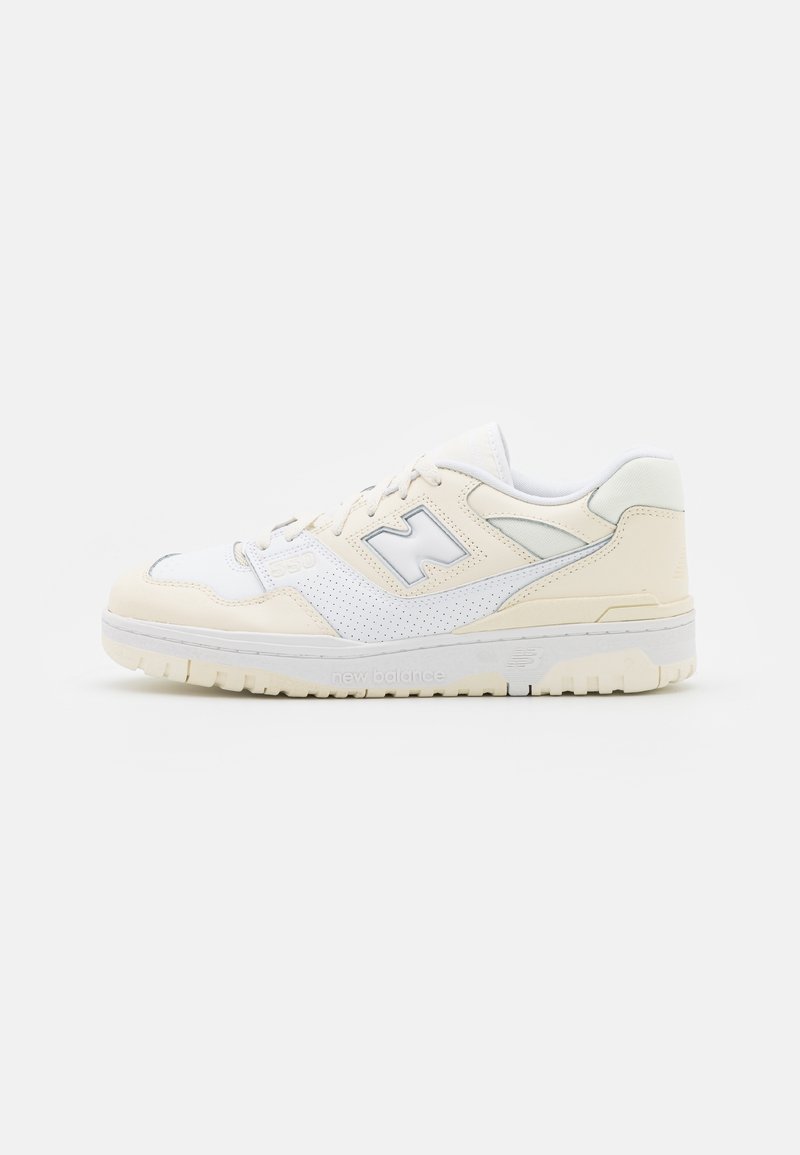 Baskets New Balance basses blanches et crème avec panneau latéral perforé, fermeture à lacets et semelle en caoutchouc, vues de profil sur fond blanc.