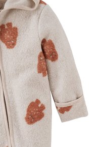 Fleece babyjas in lichtbeige met bruine berenpatronen. Voorzien van een ritssluiting en een capuchon. Zachte textuur en lange mouwen.