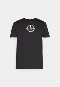 Musta puuvillainen t-paita lyhyillä hihoilla, jossa on valkoinen logo ja laakerinlehti-suunnittelu. Kauluksessa on punaisia, valkoisia ja sinisiä raitoja.
