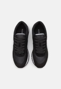 Sneakers atletici neri con una combinazione di materiali in suede e mesh, superfici testurizzate, lacci rotondi e suola bianca.