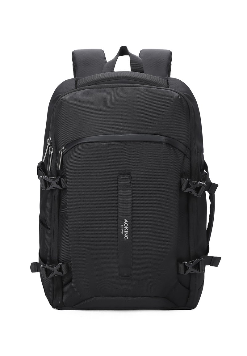 Sac à dos noir en tissu texturé, avec plusieurs zips, bretelles réglables et clips latéraux pour la compression. Présente une étiquette de logo centrale.