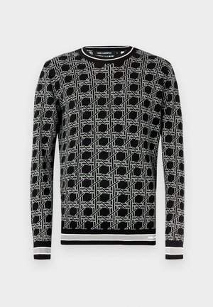 Czarny sweter z geometrycznym białym wzorem, okrągłym dekoltem, długimi rękawami oraz ściągaczami przy mankietach i dole z kontrastowymi paskami.