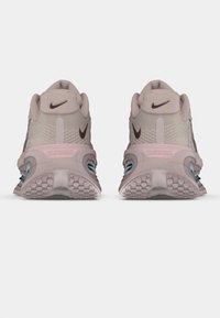 Light pink athletic shoes with a textured mesh upper, dark brown accents, and a cushioned sole featuring patterned traction.