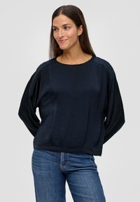 Dunkelblaues Langarmoberteil aus leichtem Stoff, mit rundem Ausschnitt und lässiger Passform, getragen mit blauen Jeans.