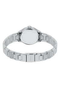 Montre en acier inoxydable avec un bracelet en métal argenté, boîtier arrondi et couronne proéminente. Présente une texture lisse et un design minimaliste.