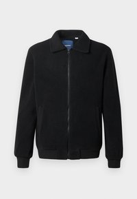 Giacca in pile nera con chiusura zip, colletto alto, polsini a coste e tasche laterali con superficie strutturata.