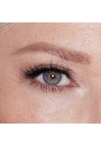 Gros plan sur un œil bleu-vert avec de longs cils noirs, un sourcil bien défini et une texture de peau lisse, mettant en valeur un maquillage des yeux subtil dans un éclairage naturel.