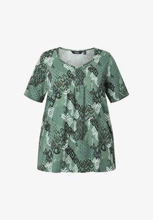 Blouse verte à manches courtes avec col rond et motifs géométriques abstraits noirs et blancs sur tout le tissu.