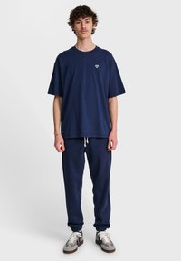 Mörkblå bomull t-shirt med en liten hjärtlogo på bröstet, i kombination med matchande mörkblå sweatpants med elastisk midja och muddar.