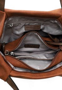 Intérieur d'un sac en toile marron avec plusieurs compartiments, doublure grise et poches zippées ; comporte des étiquettes en cuir de marque.