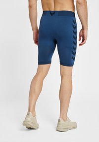 Pantaloni sportivi blu navy con un design aderente, caratterizzati da una cintura testurizzata e accenti a zigzag neri lungo i lati.