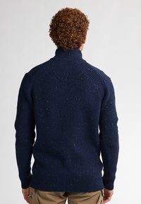 Pullover en tricot bleu marine avec un col montant, fabriqué avec un tissu texturé à motifs, des poignets et un ourlet côtelés, et des coutures d'épaule renforcées.