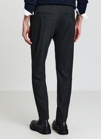 Pantaloni grigi testurizzati realizzati in tessuto intrecciato, caratterizzati da una vestibilità slim, due tasche posteriori, indossati con stivaletti neri alla caviglia.