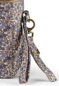 Kassi kangast, millel on lilleline muster ja pehme tekstuur, varustatud pronksist metalkinnitusega ning reguleeritava rihmaga pehmetes sinise ja roosa toones.