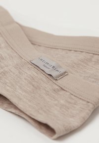 Beige stoffen ondergoed met een zachte textuur en een klein ingeweven label met de tekst "Intimissimi Natural."