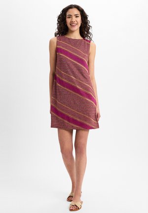 Ärmelloses Kleid in Magenta mit diagonalen goldenen und rosa Streifen. Der Stoff wirkt strukturiert, knielang, mit lockerer Passform, kombiniert mit leichten Sandalen.