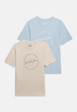 Μπεζ και γαλάζιες κοντομάνικες μπλούζες με στρογγυλές λαιμόκοψεις, κάθε μία με το κείμενο «Jack & Jones» και «Definition of Denim» τυπωμένο σε κυκλικό σχέδιο.
