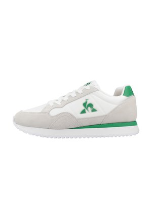 Baskets avec une tige en cuir blanc, des accents en daim gris, un logo vert et une semelle en caoutchouc. Elles disposent d'une pointe arrondie et de lacets plats.