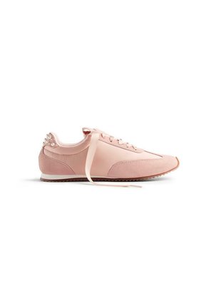 Baskets de sport roses présentant un mélange de cuir lisse et de textures en daim, avec des lacets en ruban et des accents en perles sur le talon.