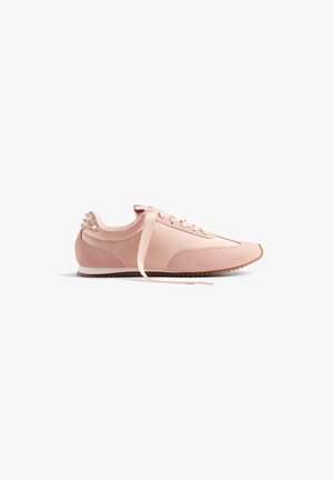 Zapatillas deportivas rosas que presentan una combinación de cuero suave y texturas de ante, con un cordón de cinta y acentos de perlas en el talón.