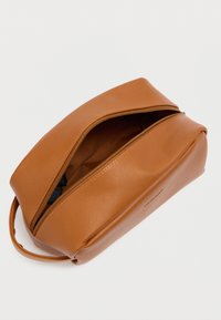 Καφέ δερμάτινο τσαντάκι με λεία υφή, ορθογώνιο σχήμα και κλείσιμο με φερμουάρ. Διαθέτει λαβή για εύκολη μεταφορά.