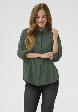 Dark green button-up shirt with a collar, long sleeves rolled to the elbows, and a relaxed fit. Cotton-like texture and rounded hem.