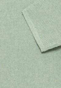 Tissu en maille côtelée vert clair, présentant une surface texturée et un revers plié, affichant un motif cohérent sur toute la surface.