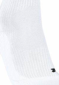 Chaussette de sport blanche avec une texture côtelée, présentant un logo noir à la cheville. Tissu lisse avec des zones de renforcement à la pointe et au talon.