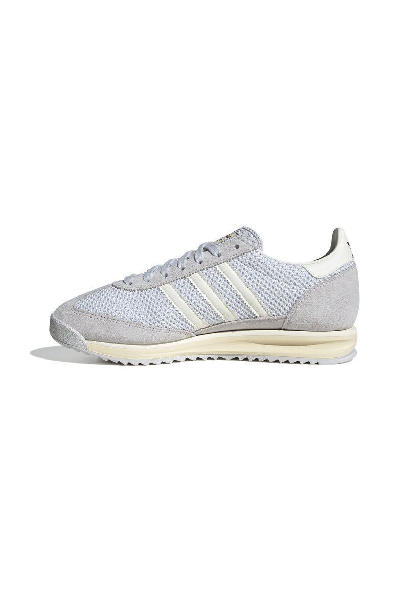Gray athletic shoes with a mesh and suede upper, featuring three white stripes, round laces, and a textured outsole for grip.