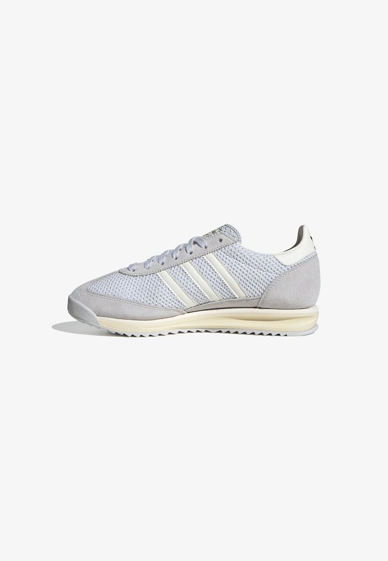 Gray athletic shoes with a mesh and suede upper, featuring three white stripes, round laces, and a textured outsole for grip.