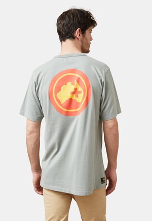 Camiseta de algodón gris claro con un gran gráfico circular en naranja y amarillo en la parte de atrás, que representa un mapa de Australia con una cruz.