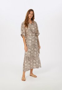 Lightweight, snake print dress in beige and brown hues; features a button-down front, short sleeves, a tie waist, and a flowy silhouette.