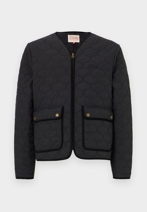 Chaqueta negra acolchada con cremallera frontal, dos bolsillos delanteros y cuello redondo. Presenta herrajes dorados y un ribete negro contrastante alrededor de los bolsillos.