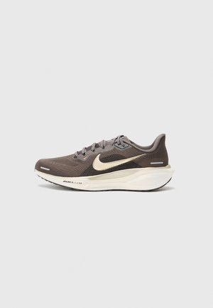 Baskets de sport grises avec tige en mesh, logo en or en forme de virgule, semelle rembourrée et semelle extérieure noire. Dispose de lacets et d'un talon structuré pour le soutien.