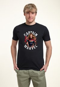 Czarna bawełniana koszulka z grafiką postaci w czerwono-niebieskim kostiumie, otoczona napisem "CAPTAIN MARVEL" w wyraźnych, białych literach.