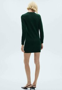 Abito maglione verde scuro con maniche lunghe, scollo rotondo e silhouette aderente, realizzato in un tessuto morbido, che arriva a metà coscia.