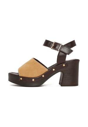 Brązowo-beżowy sandał na obcasie dla kobiet z paskiem wokół kostki, złotą klamrą, drewnianą podeszwą i detalami z ćwiekami po boku.