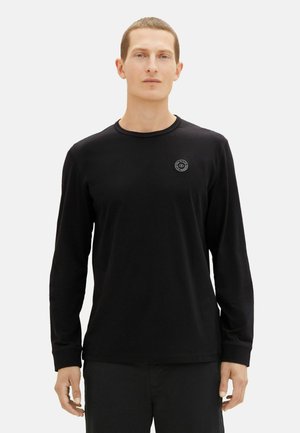 Zwarte T-shirt met lange mouwen van zachte stof, voorzien van een ronde halslijn en een klein rond logo op de borst, met aansluitende mouwen en een gladde textuur.